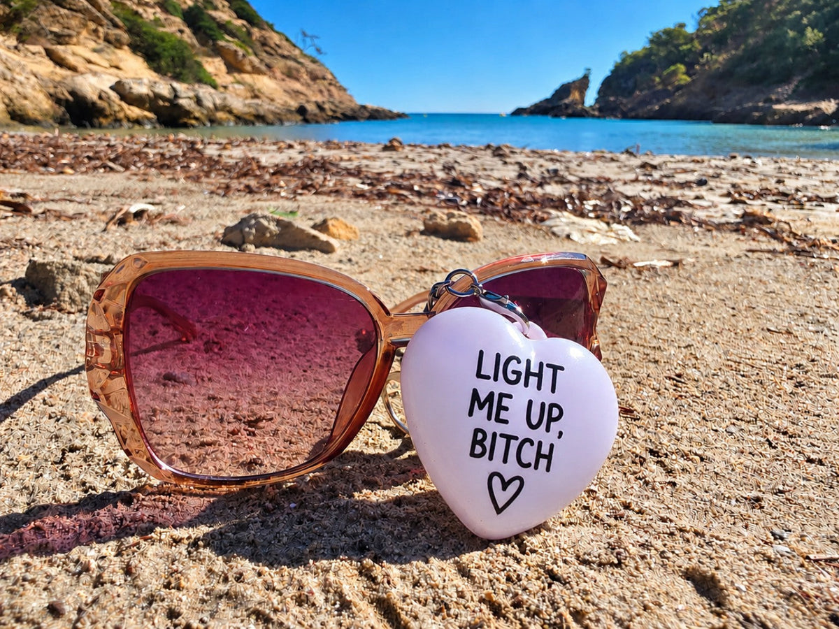 Light Me Up, Bitch heart charm on sunglasses at Mallorca beach